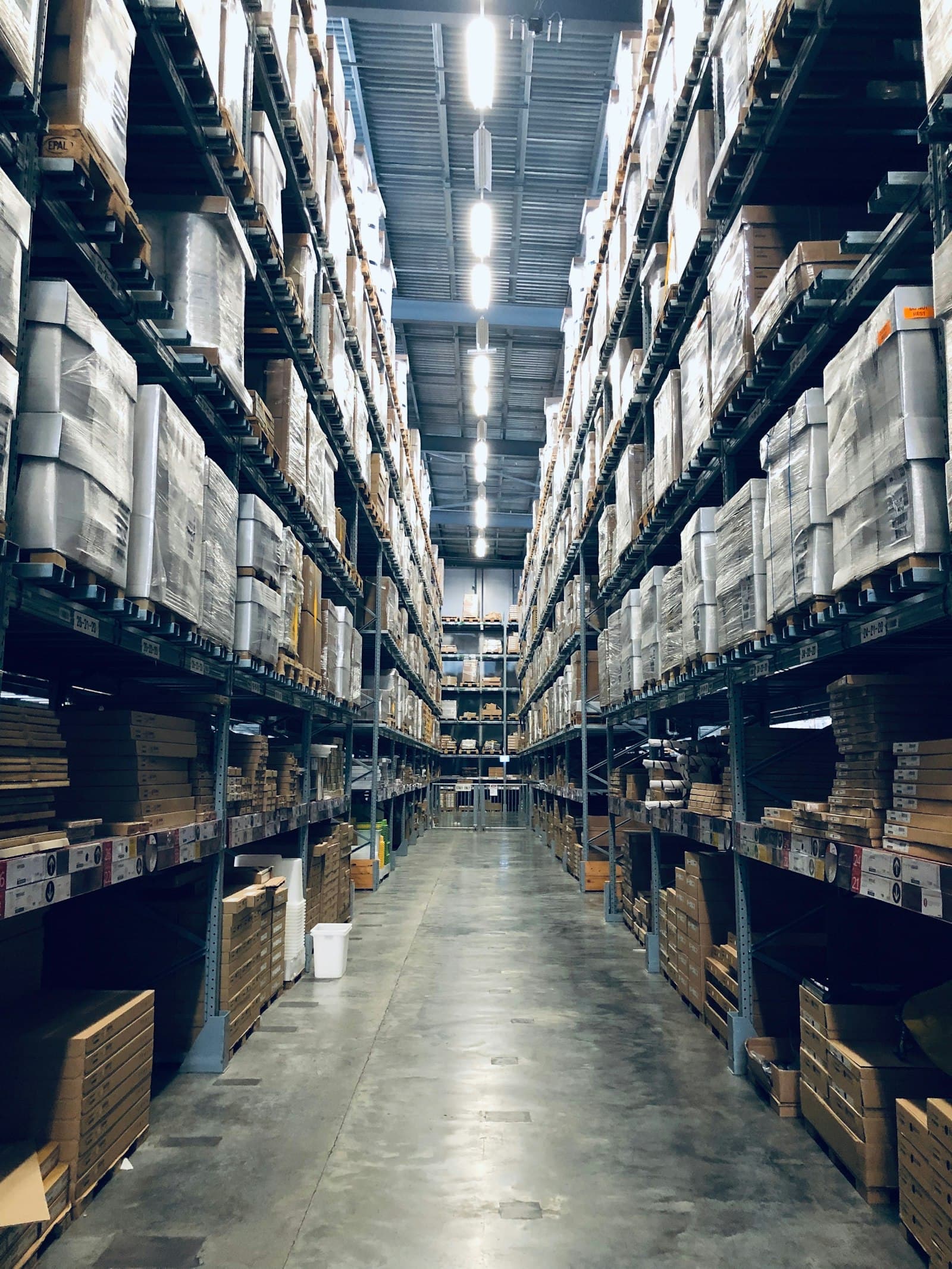 Pallets of stock stacked to the ceiling in a warehouse aisle